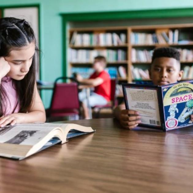 Kids reading at table in library