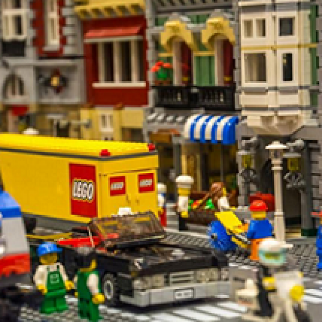 Storefronts made from legos and Lego word on side of truck and little lego people 