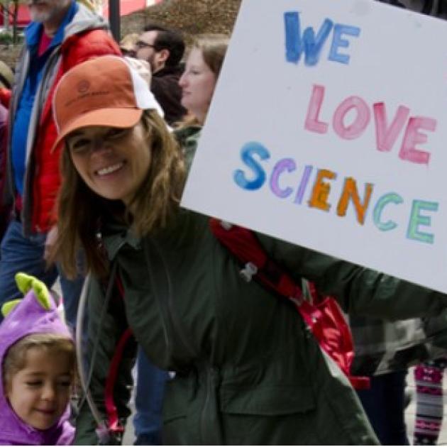 Woman with child and sign saying We Love Science