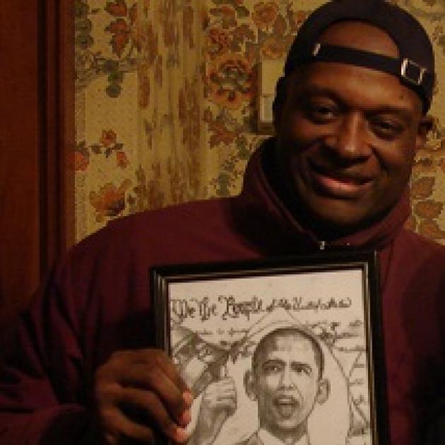 Black man smiling and holding an illustration of Obama