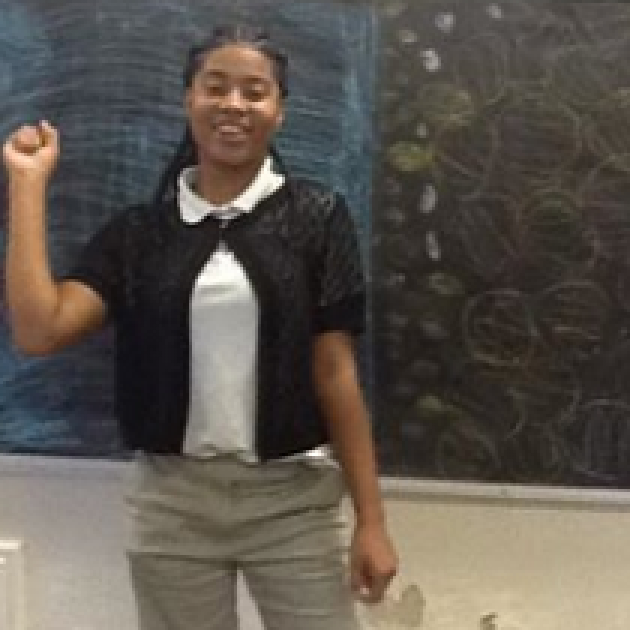 Young black woman standing in front of a blackboard with a smile and raising her right hand