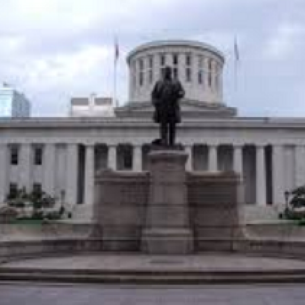 Large black statue of a man on a pedestal in front of a large white government building with many columns