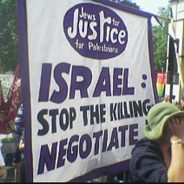 People protesting outside with sign saying Israel stop the killing, negotiate