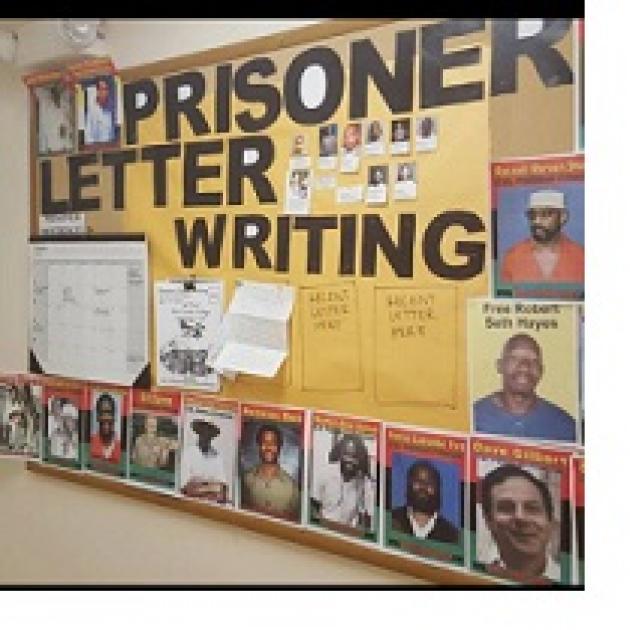 Bulletin board on the wall with words Prisoner Letter Writing and photos of a lot of men