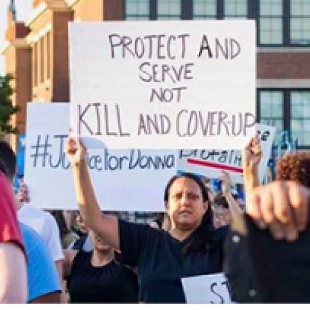 Woman outside holding a sign that says Protect and Serve not Kill and Coverup