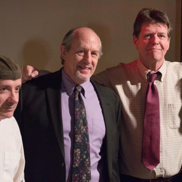 Four middle aged white guys, some in suits, standing together with their arms around each other