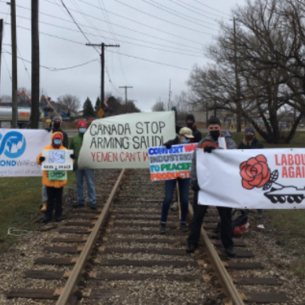 People holding signs on a railroad track