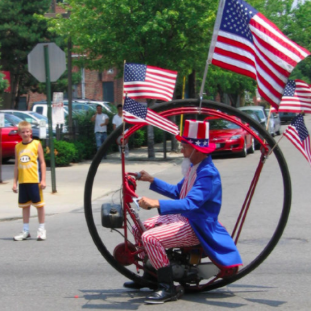 Uncle Sam in a round bike with flags in the parade