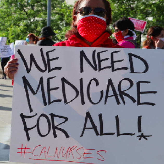 Person holding sign saying We Need Medicare for All