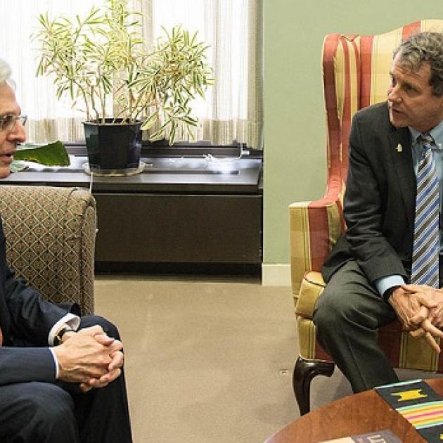 Merrick Garland and Sherrod Brown sitting in chairs looking at each other