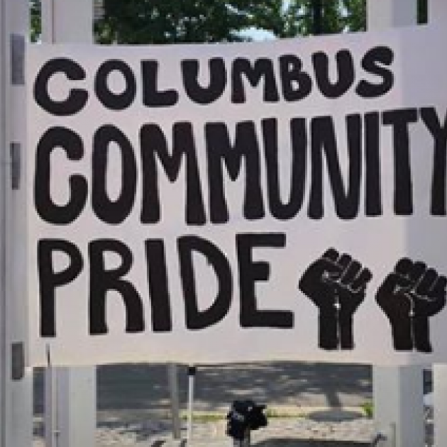 Big white outdoor sign saying Columbus Community Pride with two fist drawings