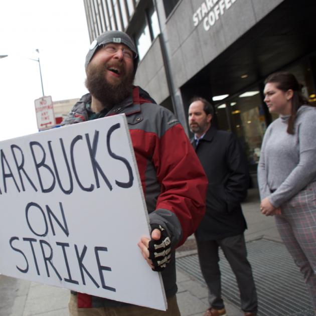 Guy outside Starbucks holding a sign saying Starbucks on strike