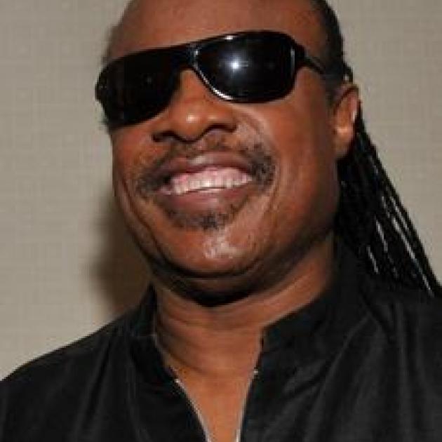Smiling black man with big sunglasses and long braids in a black shirt