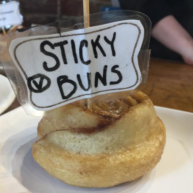 A cinnamon bun with a sign on it saying Sticky Buns