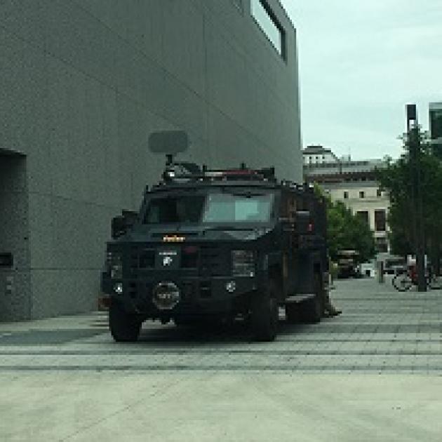 Large army-looking tank coming out of a narrow street