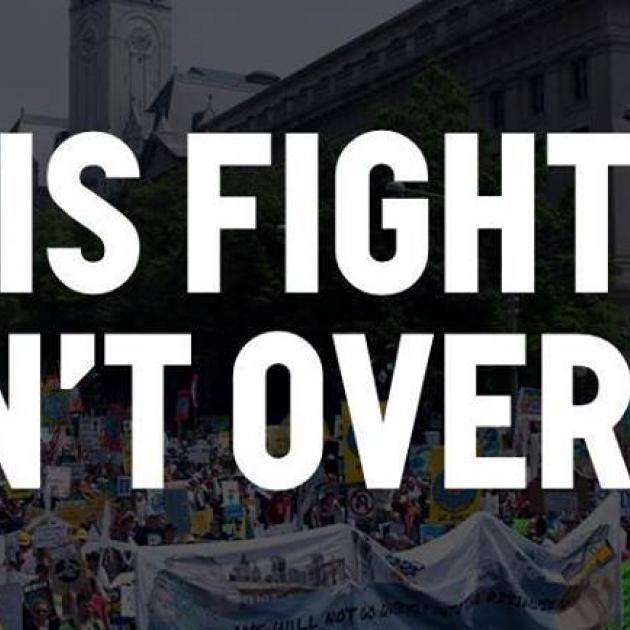 Black and white background of people at a rally and the words THIS FIGHT ISN'T OVER