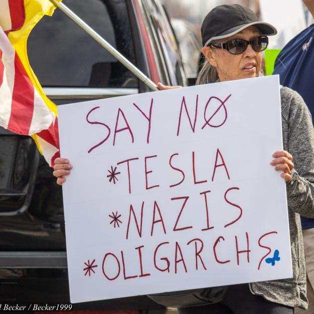 Woman holding sign at Tesla protest