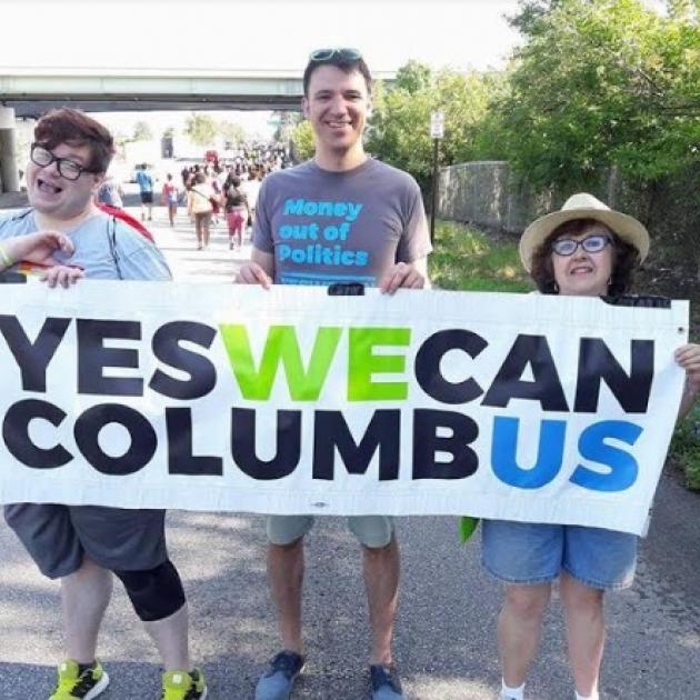 People outside holding a Yes We Can banner