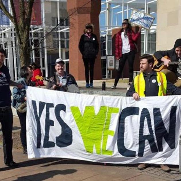 People holding a Yes We Can sign outside a brick building