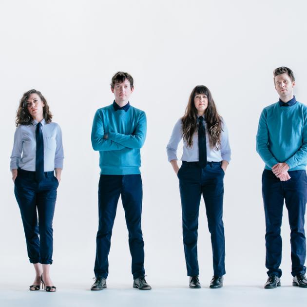 Four white people standing in a row dressed the same