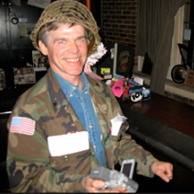 White man with a helmet on a big smile, and a camouflage jacket