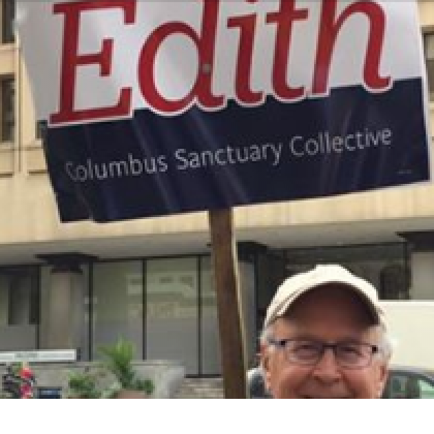 Man holding sign on stick that says Edith Columbus Sanctuary Collective