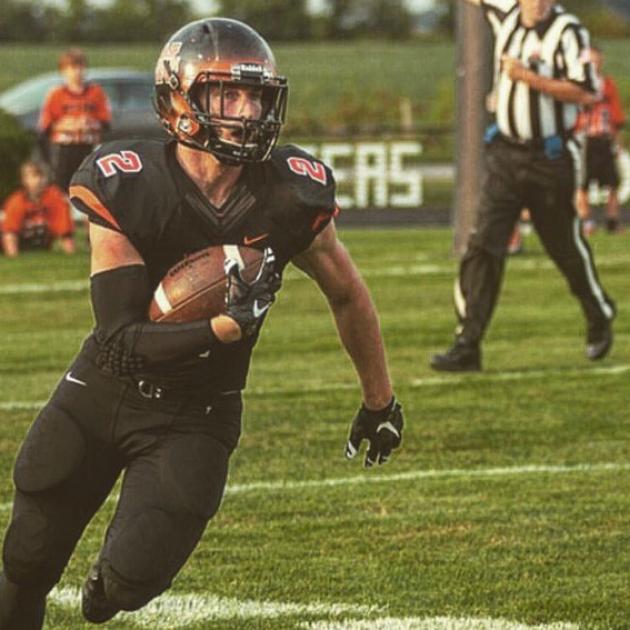 Football player running with the ball in his arm in brown and orange uniform