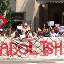 Words Abolish ICE real big on a sign behind people protesting
