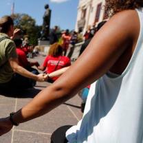 People sitting on ground holding hands and women in foreground holding someone's hand
