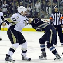 Two hockey players fighting on the ice with a ref looking on