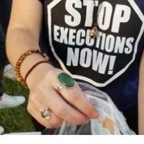 Woman from neck down wearing black T-shirt with words Stop Executions Now