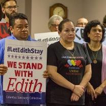Latino people posing for camera looking grim, one man holding a sign that says #LetEdithStay We Stand with Edith