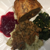 Top down view of a white plate with red cranberry sauce, a brown skinned potato something green and leafy on the side and what looks like rice with something brown on top