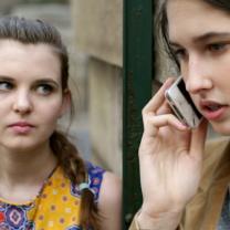 A woman on the phone and another woman looking at her in an alarmed way