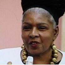 Black woman with A large gold necklace talking into a mic