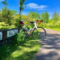Ten speed white man's bike parked on the grass next to a trail and a sign that says Rail Trail