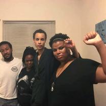 Four young black people one with fist in the air