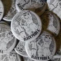 Pile of white and black buttons with drawing of four black kids raising fists on them