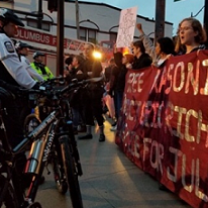 Police on bikes facing off at a banner held by people saying Free Masonique