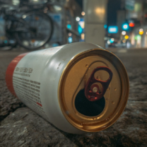Empty beer can on the ground outside at night