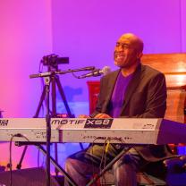 Bald black man singing at a keyboard