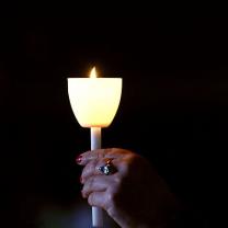 A hand holding up a candle in the dark