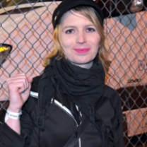 Young blonde woman in a black outfit raising her fist
