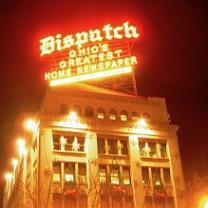 Bright yellow and red neon sign saying Dispatch Ohio's greatest homes newspaper above a big fancy building at night