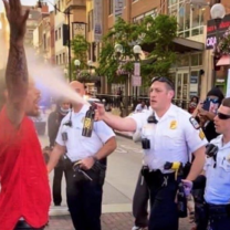 Cop spraying black man with hands in air