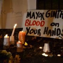 Candles and a sign that says "Mayor Ginther Blood on your hands"