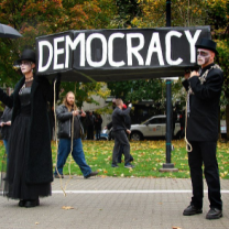 People in a funeral procession holding a democracy sign
