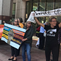 People outside holding banners one saying Wake Up