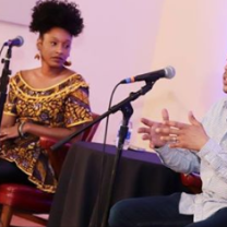 Two people on stage talking into mics