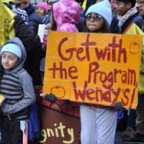 People standing outside and young girl holding a sign that says Get with the program, Wendy's